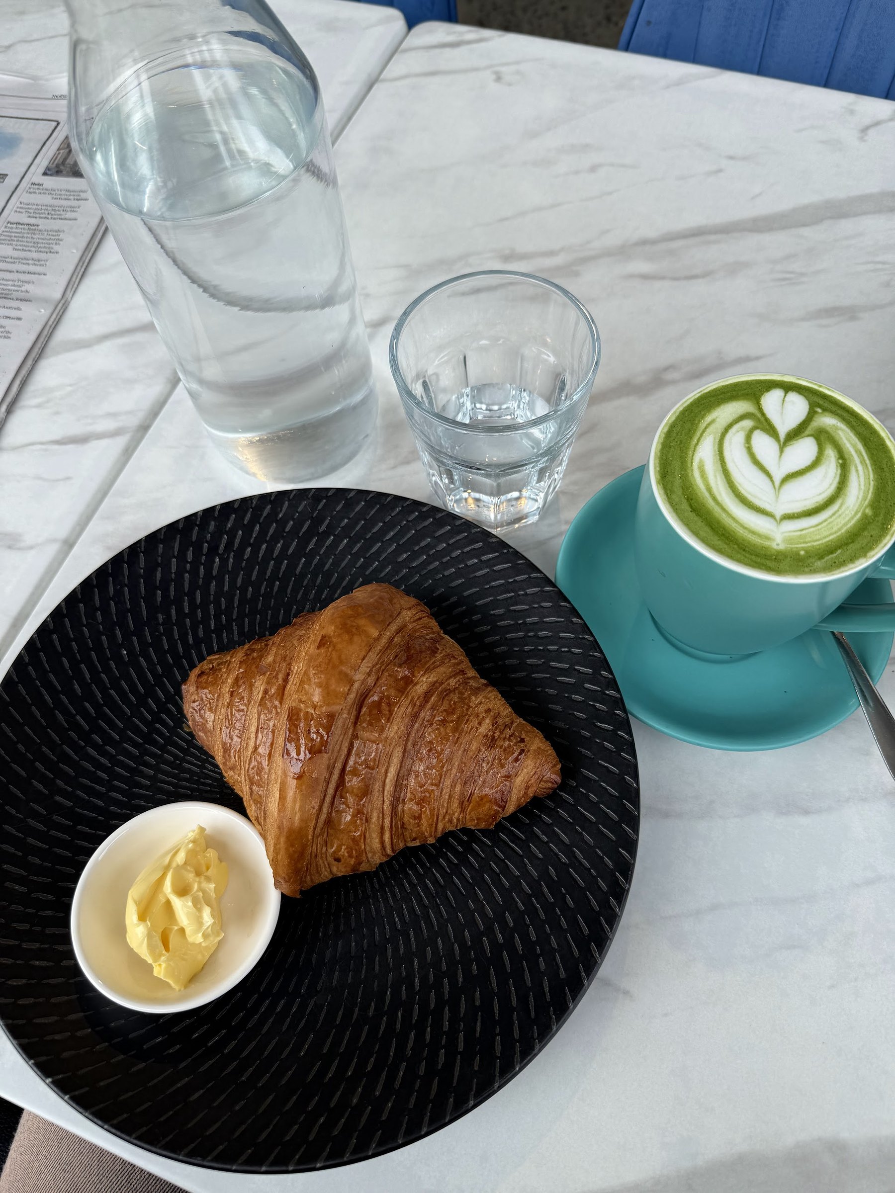A croissant with butter and a matcha latte