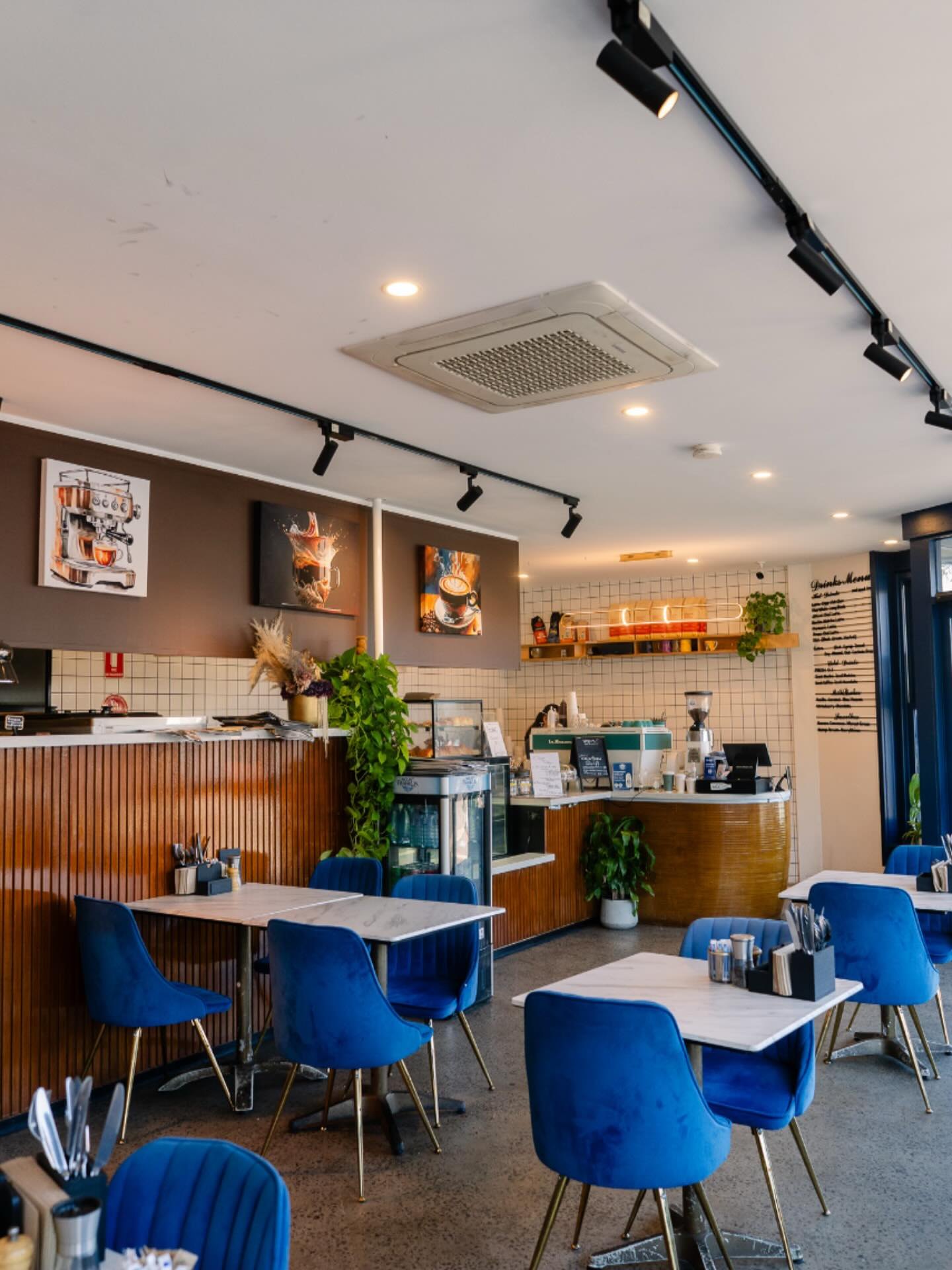 Blue velvet chairs and marble tables inside the cafe
