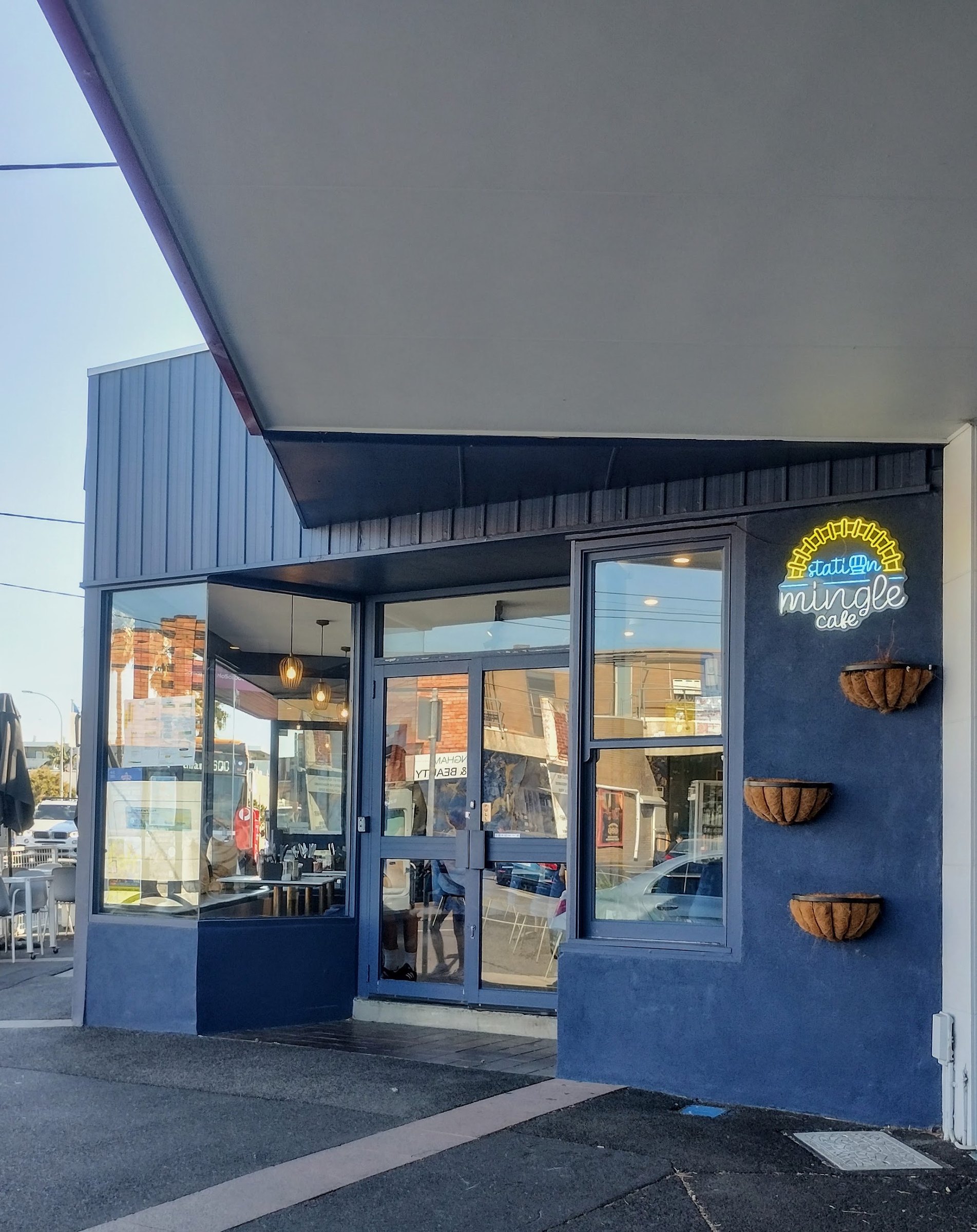 The navy shopfront of Station Mingle Cafe with its neon sign